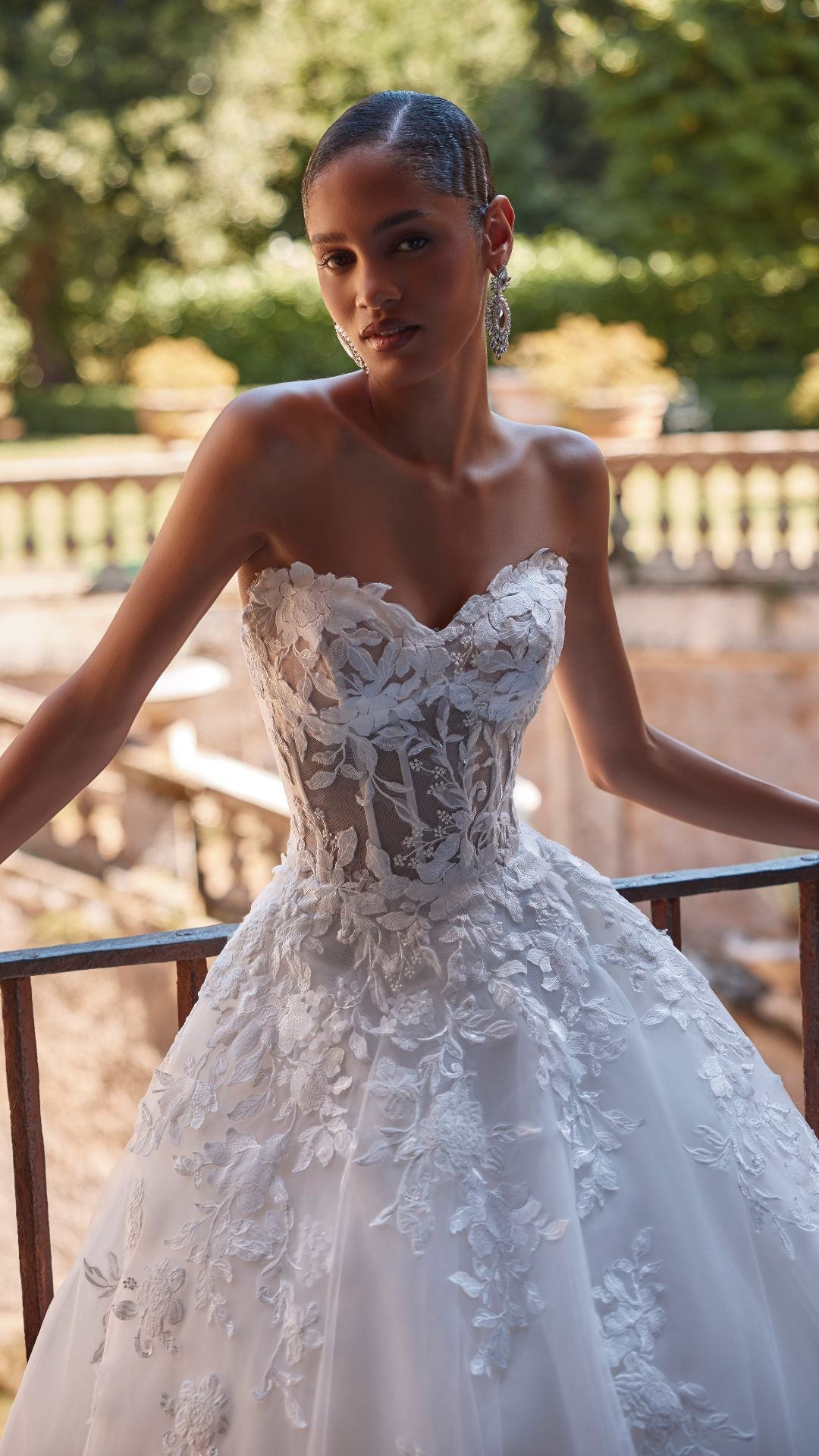 Brautkleid Veni Infantino präsentiert eine Braut im Atelier mit schöner Landschaft im Hintergrund.