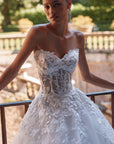 Brautkleid Veni Infantino präsentiert eine Braut im Atelier mit schöner Landschaft im Hintergrund.