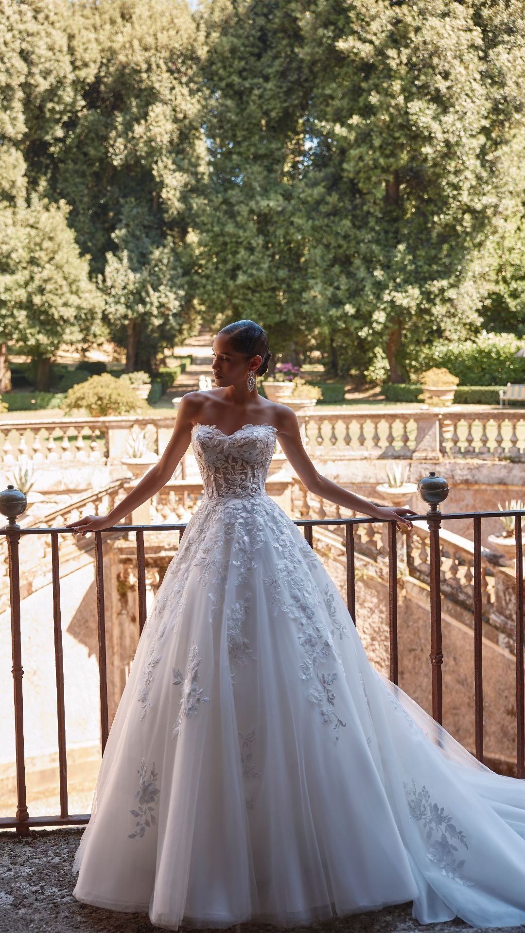 Brautkleid Veni Infantino präsentiert eine Braut im Atelier mit schöner Landschaft im Hintergrund.