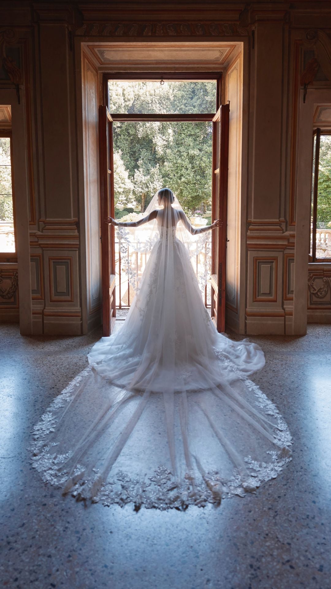 Brautkleid Veni Infantino präsentiert eine Braut im Atelier mit schöner Landschaft im Hintergrund.