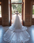 Brautkleid Veni Infantino präsentiert eine Braut im Atelier mit schöner Landschaft im Hintergrund.