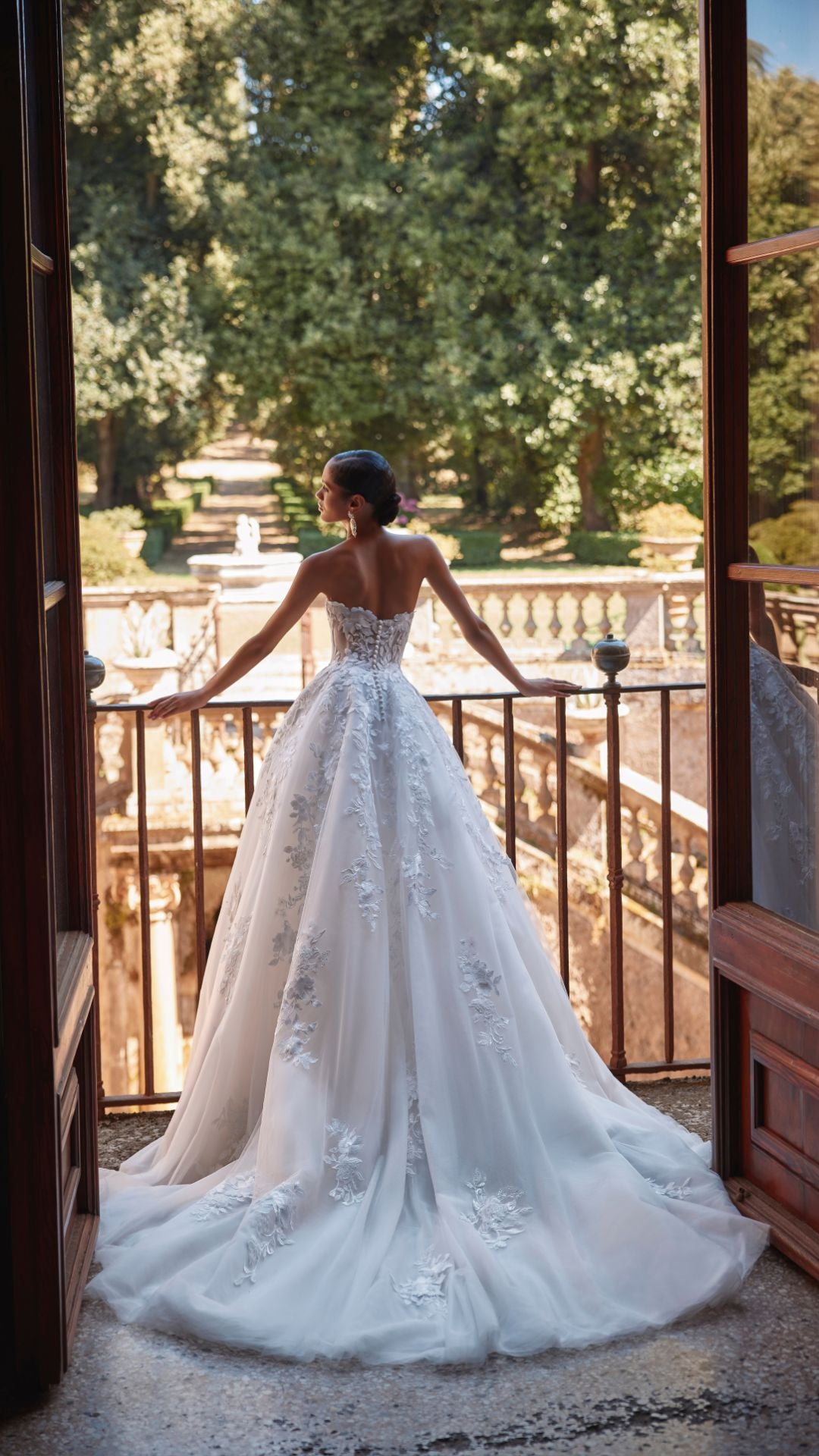 Brautkleid Veni Infantino präsentiert eine Braut im Atelier mit schöner Landschaft im Hintergrund.