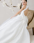 Elegantes Brautkleid von Morilee, präsentiert mit zarten Blumen im Hintergrund, perfekte Wahl für den großen Tag.