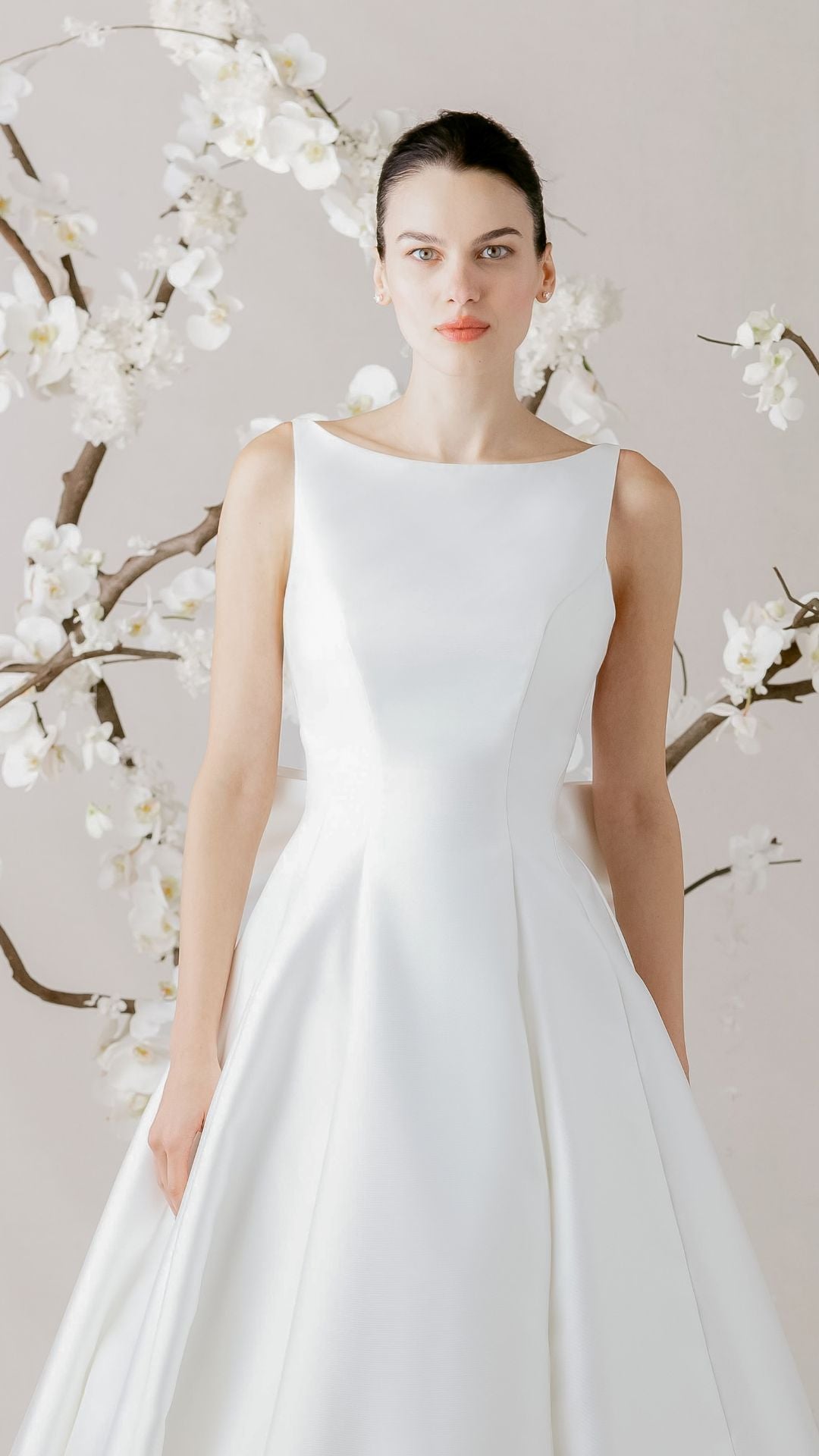 Elegantes Brautkleid von Morilee, präsentiert mit zarten Blumen im Hintergrund, perfekte Wahl für den großen Tag.